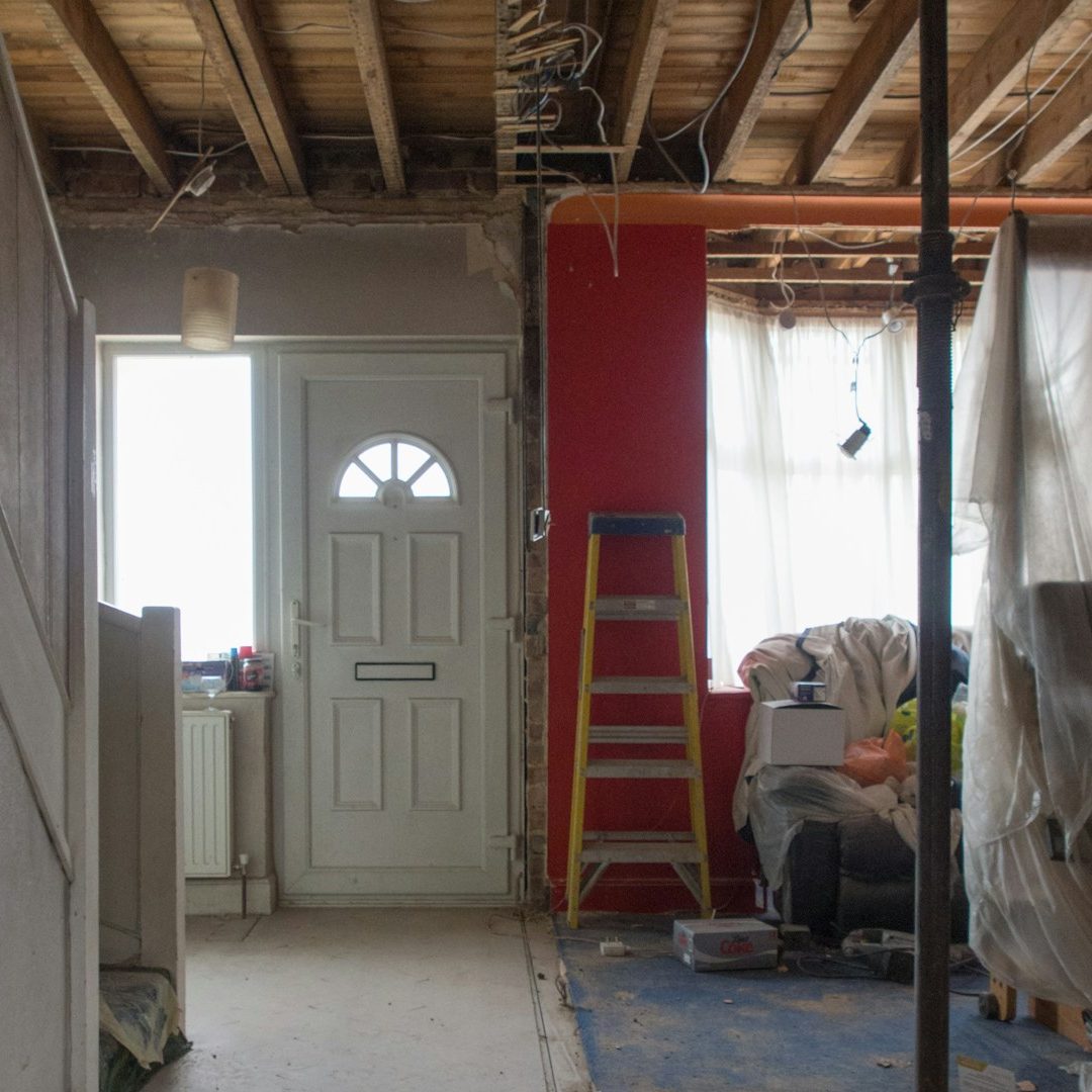 Renovation scene showing an open doorway, ladder, and unfinished living space.